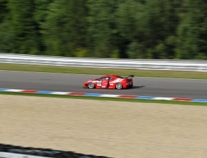 selective focus photo of red and white racing car on black top road thumbnail