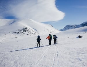 three person walking on snow during daytime thumbnail