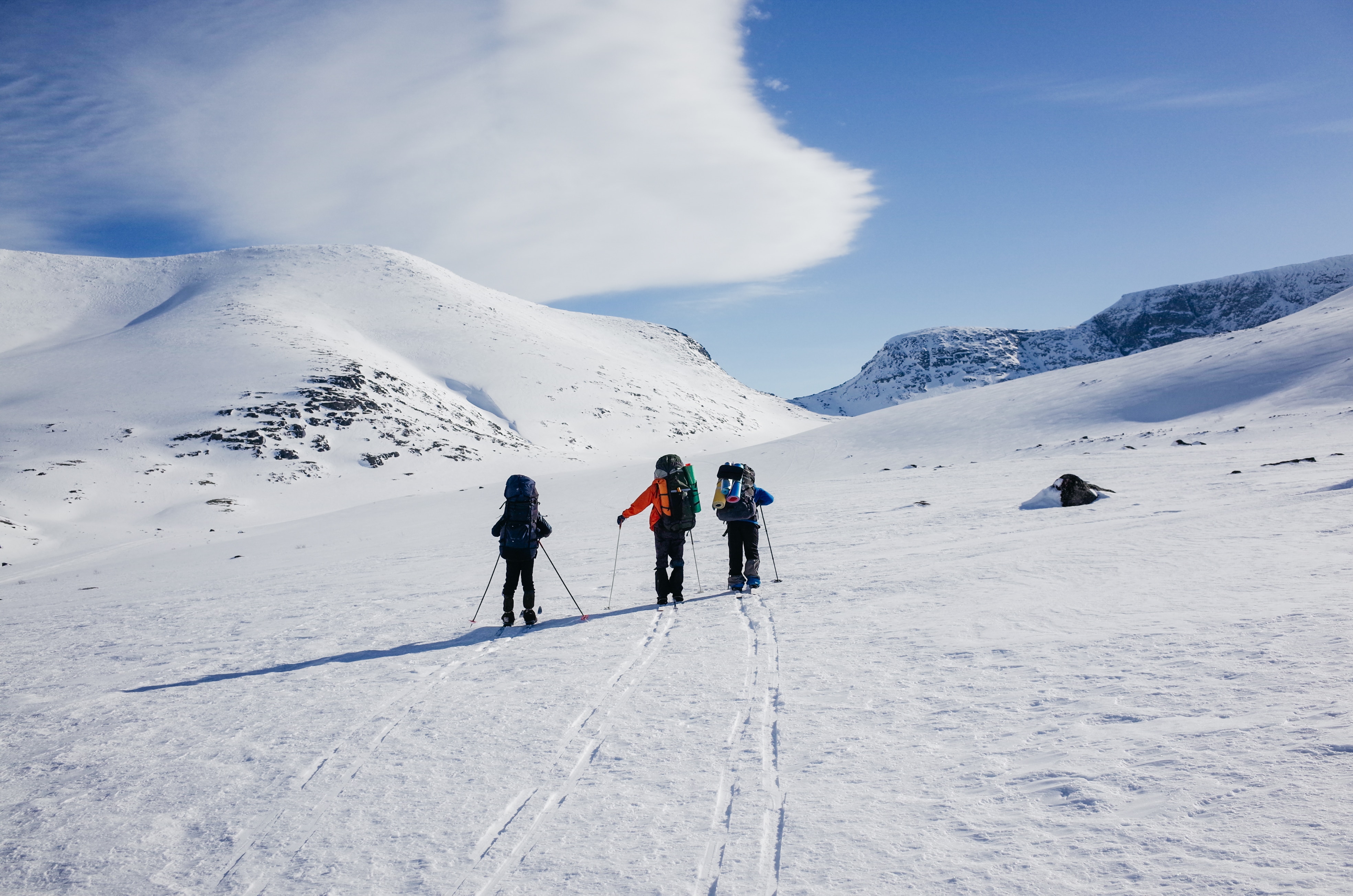 three person walking on snow during daytime