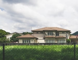 white and brown concrete house near green fields during daytime thumbnail