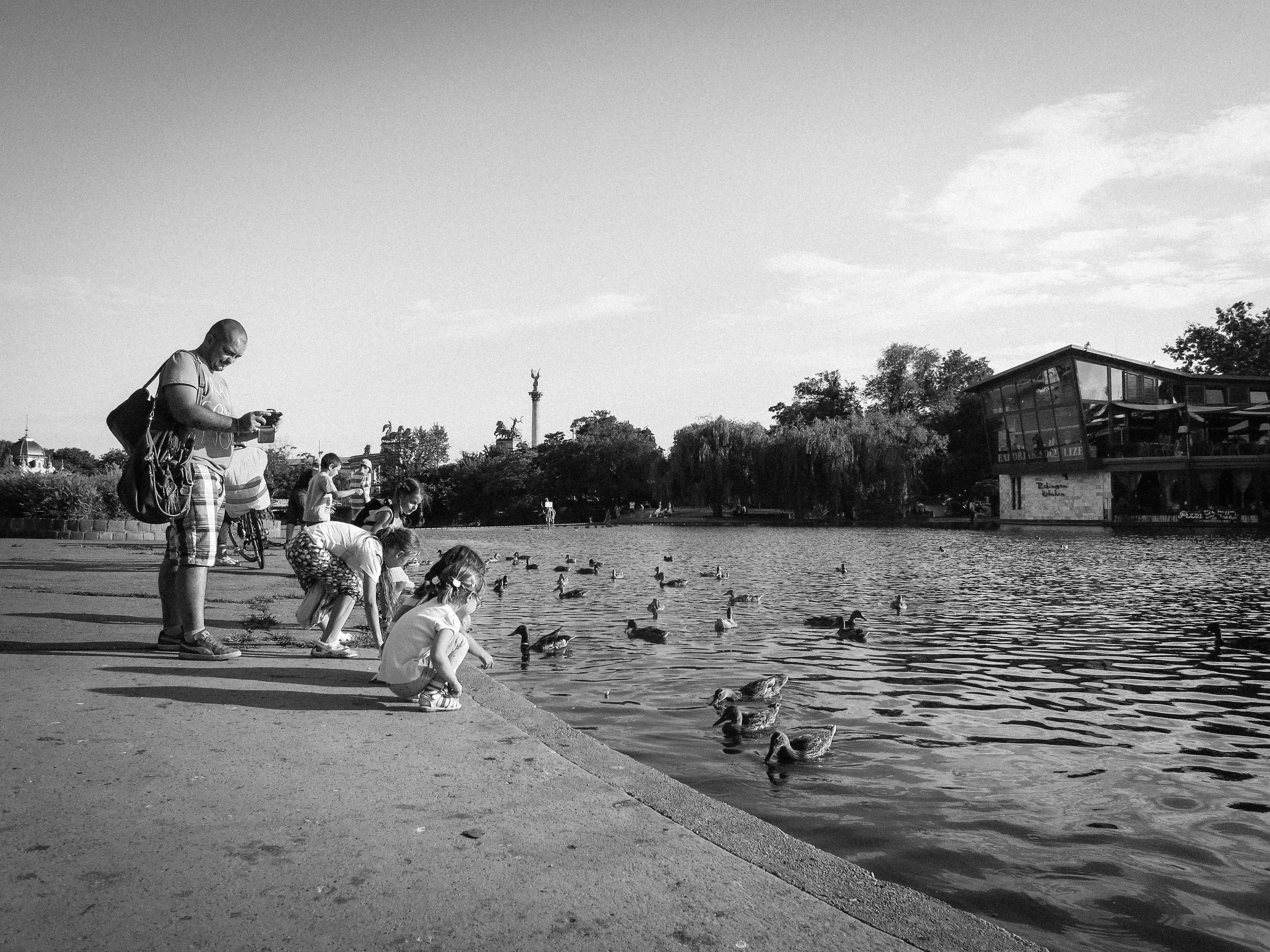 grayscale photo of kids feeding duck