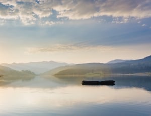 panoramic photography of sunrise with body of water and mountains thumbnail