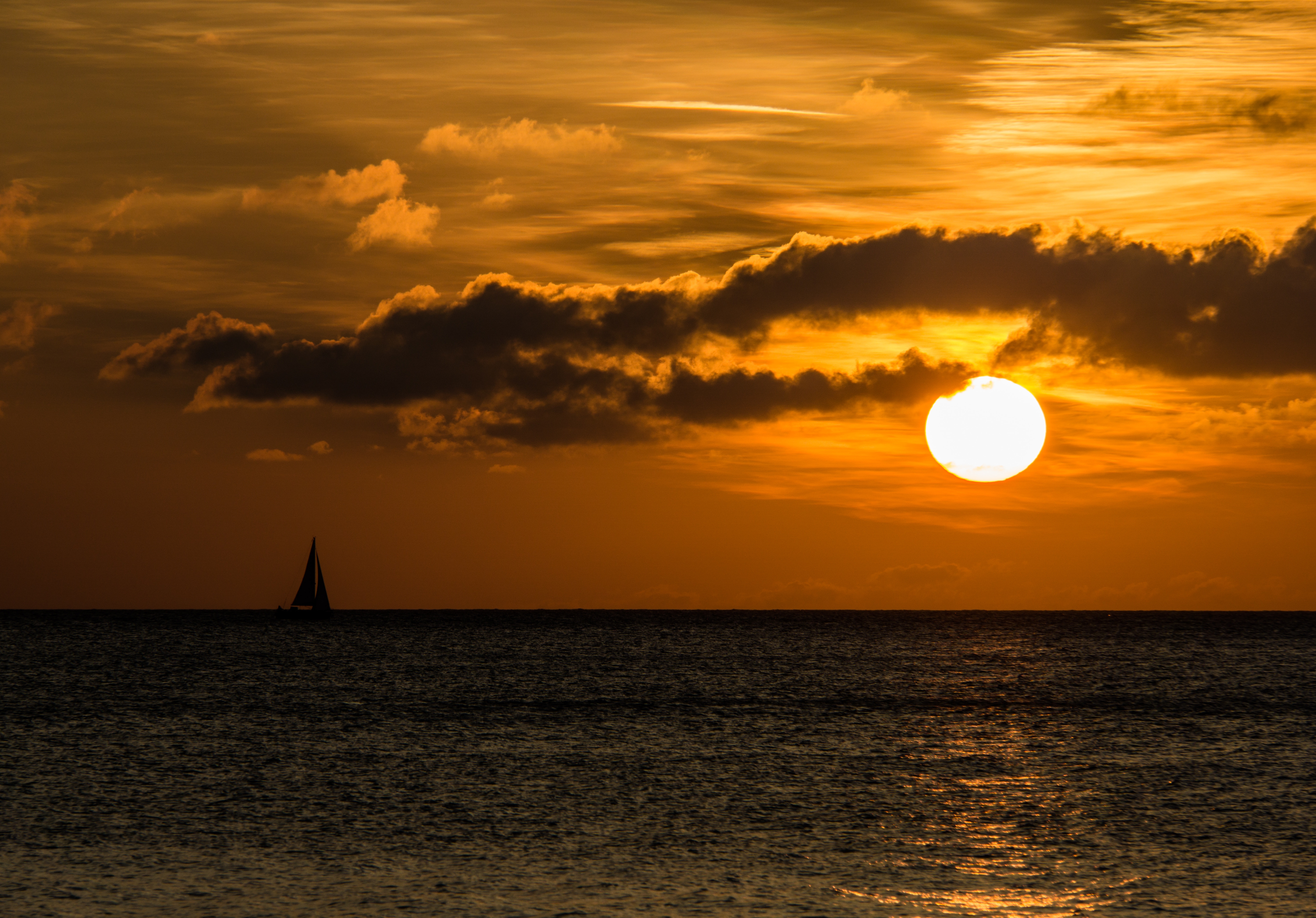 silhouette of sailboat on body of water during sunset