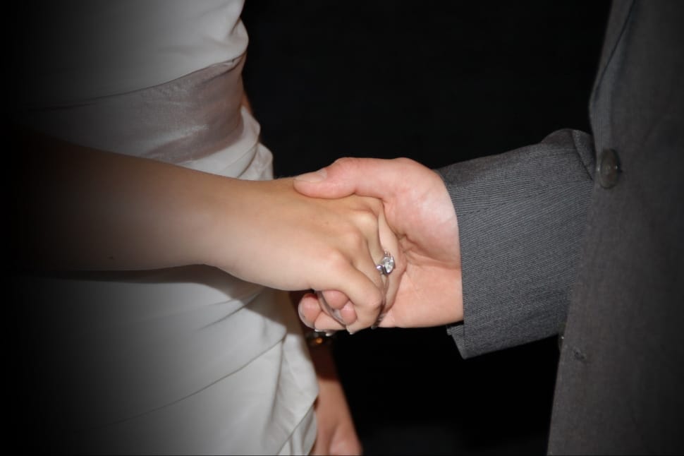 man holding woman hand in formal dress during nightime preview