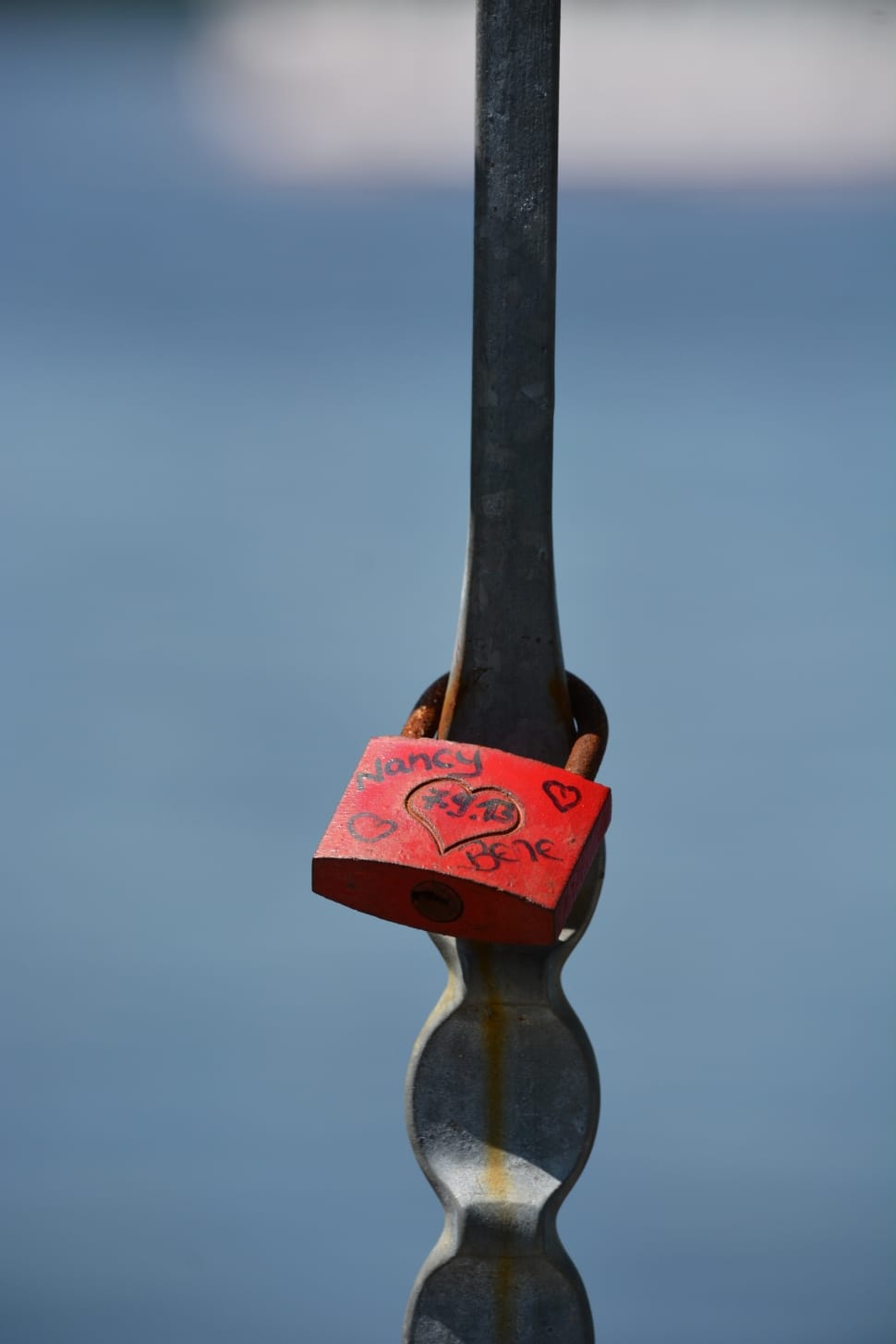 red padlock on gray metal fence preview