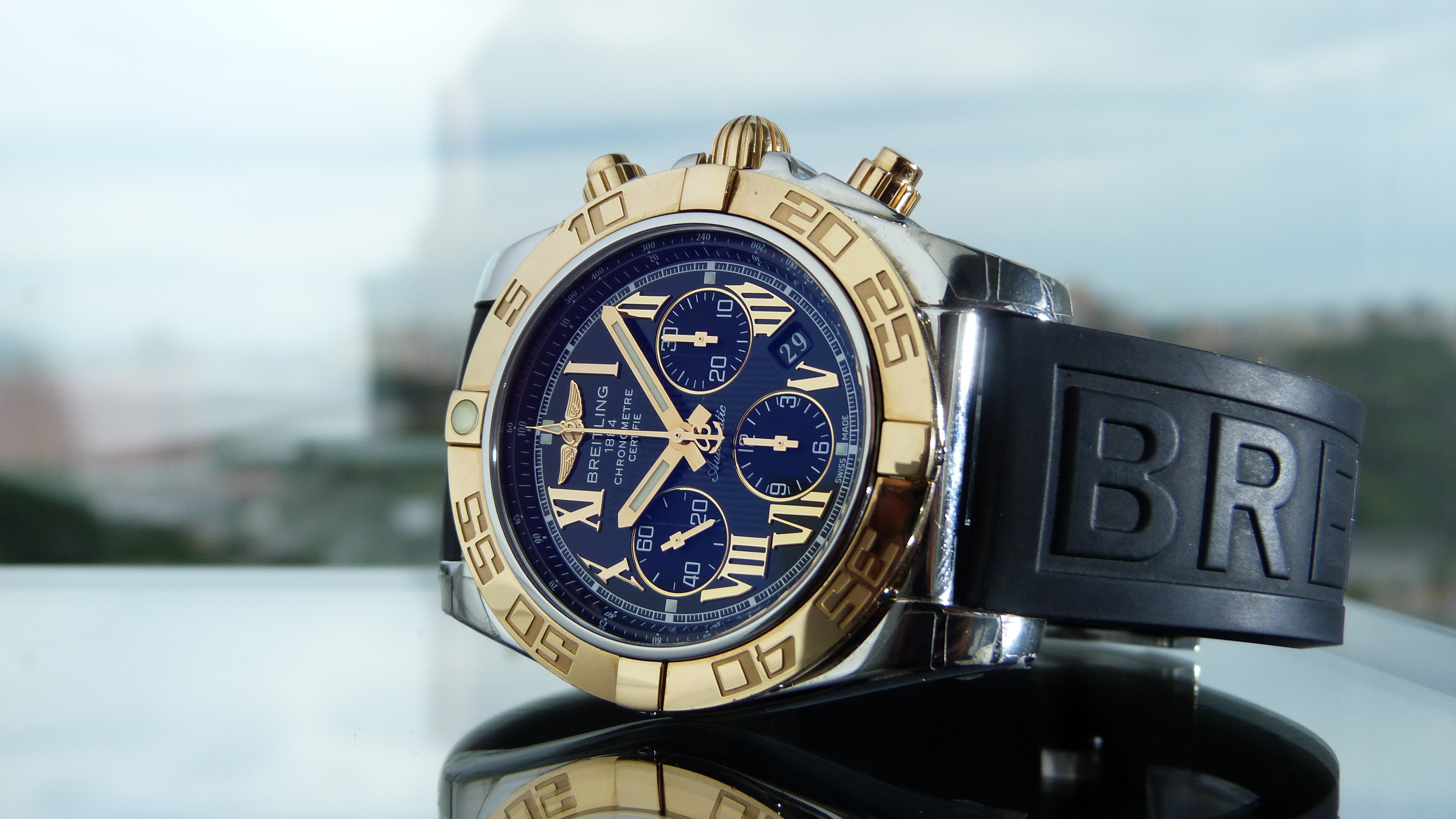 black rubber strapped gold round framed blue face chronograph watch