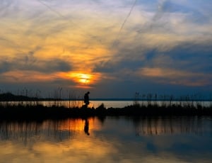 silhouette photo of man near river thumbnail