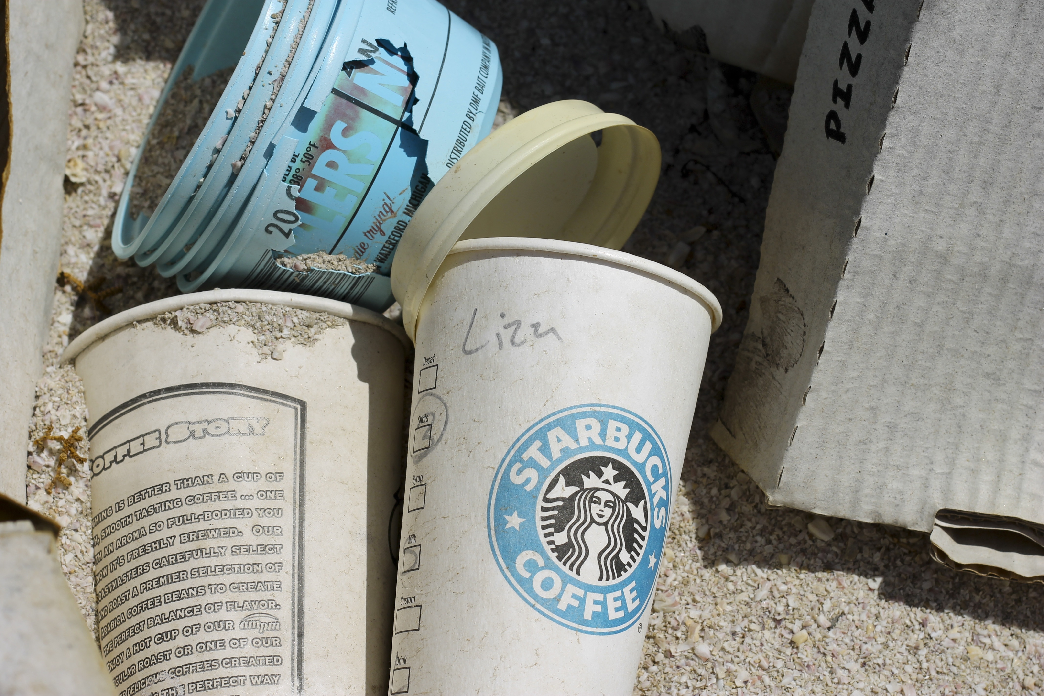 white and blue Starbucks Coffee plastic cup beside blue plastic bucket