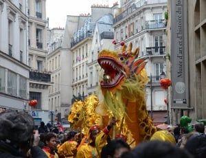 yellow dragon dance surrounded by group of people during daytime thumbnail