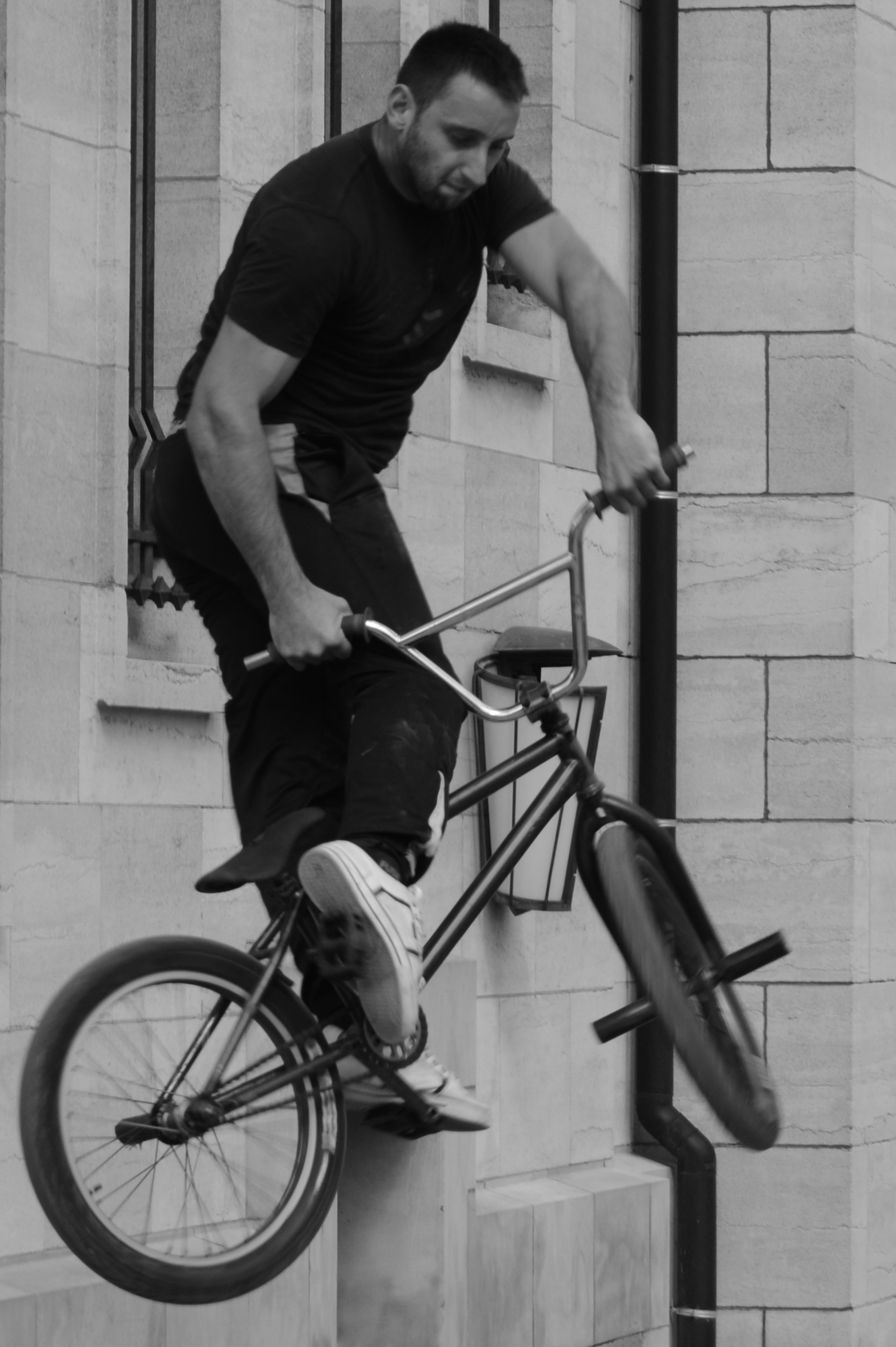 gray scale photo of man riding bmx
