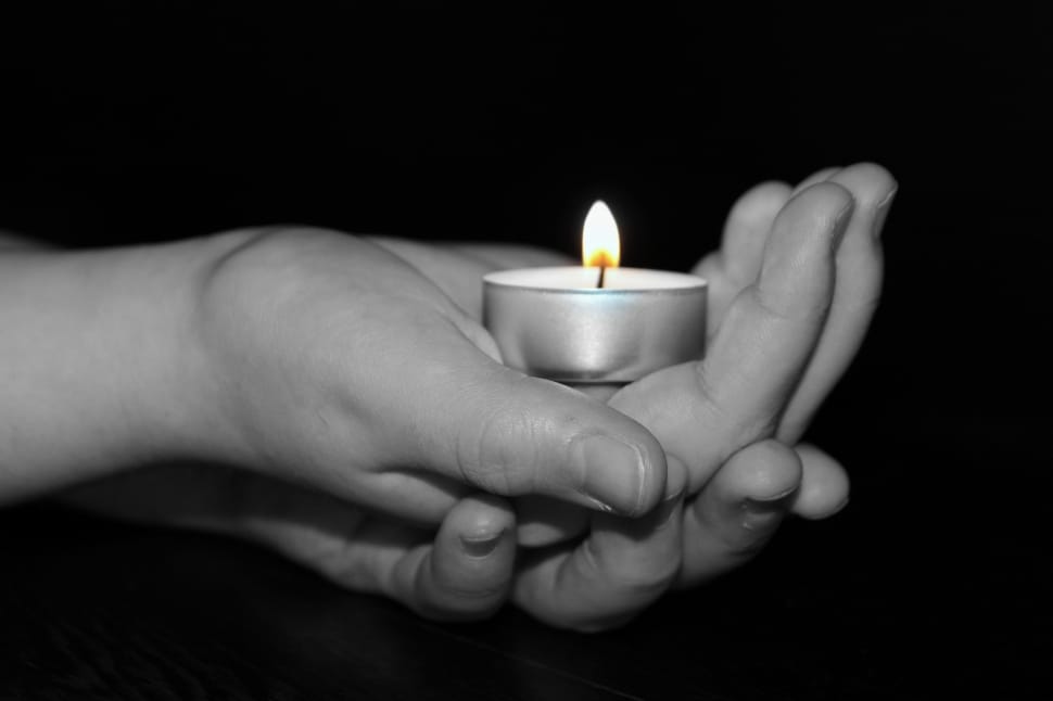 gray scale photo of hand holding tealight candle preview