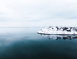body of water near ice land under cloudy sky during daytime thumbnail