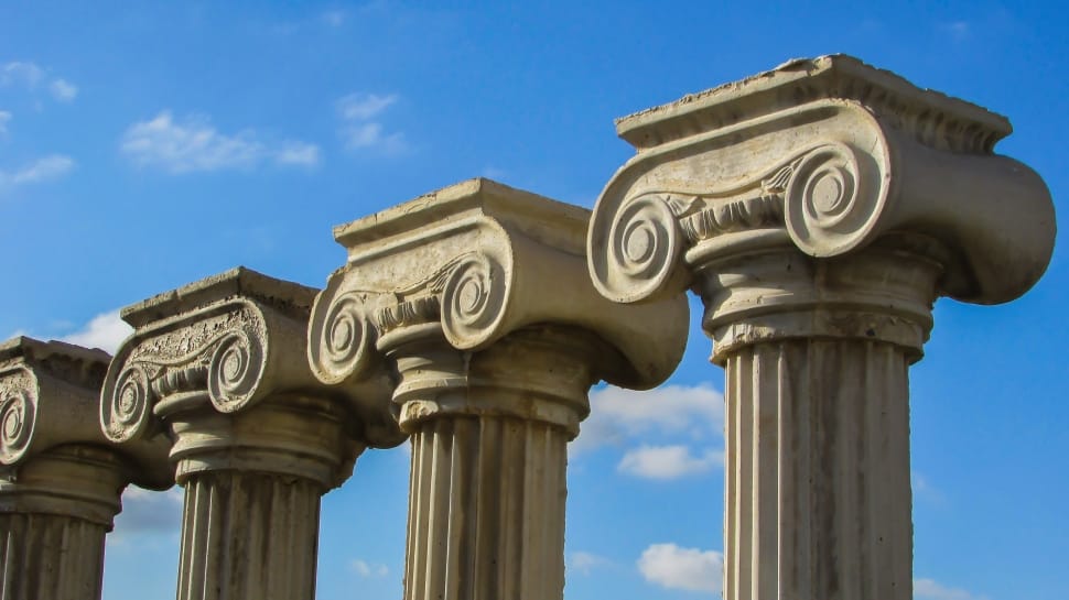 four gray concrete pillars under blue sky preview