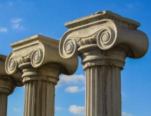 four gray concrete pillars under blue sky thumbnail