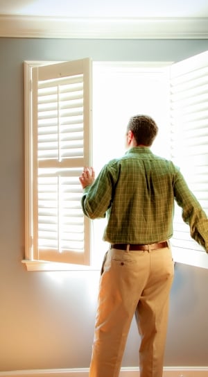 man in green checkered dress shirt near window thumbnail