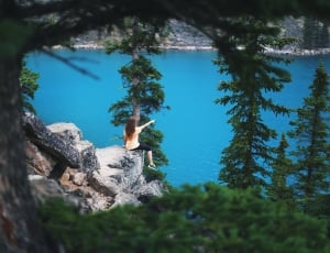 photogaphy of person sitting on rock cliff pointing at the horizon thumbnail