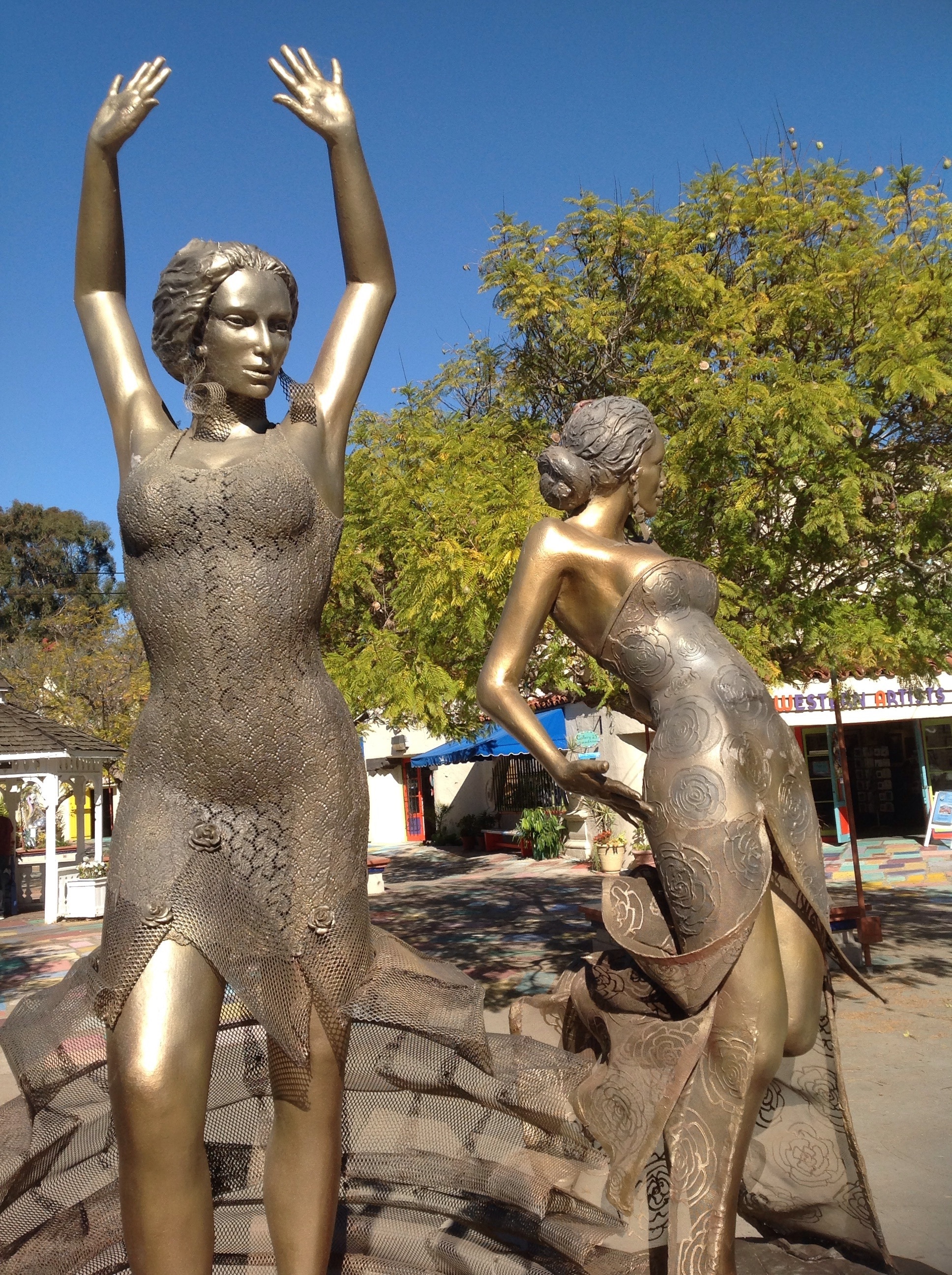 two brass woman statues on daylight