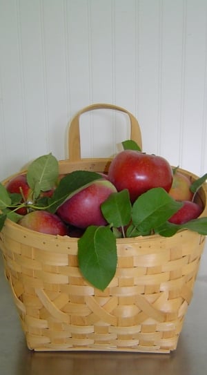 ripe apples with leaves in brown wicker basket on grey surface thumbnail