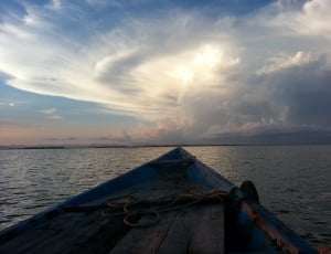 blue and brown wooden boat on body of water under cloudy sky during daytime thumbnail