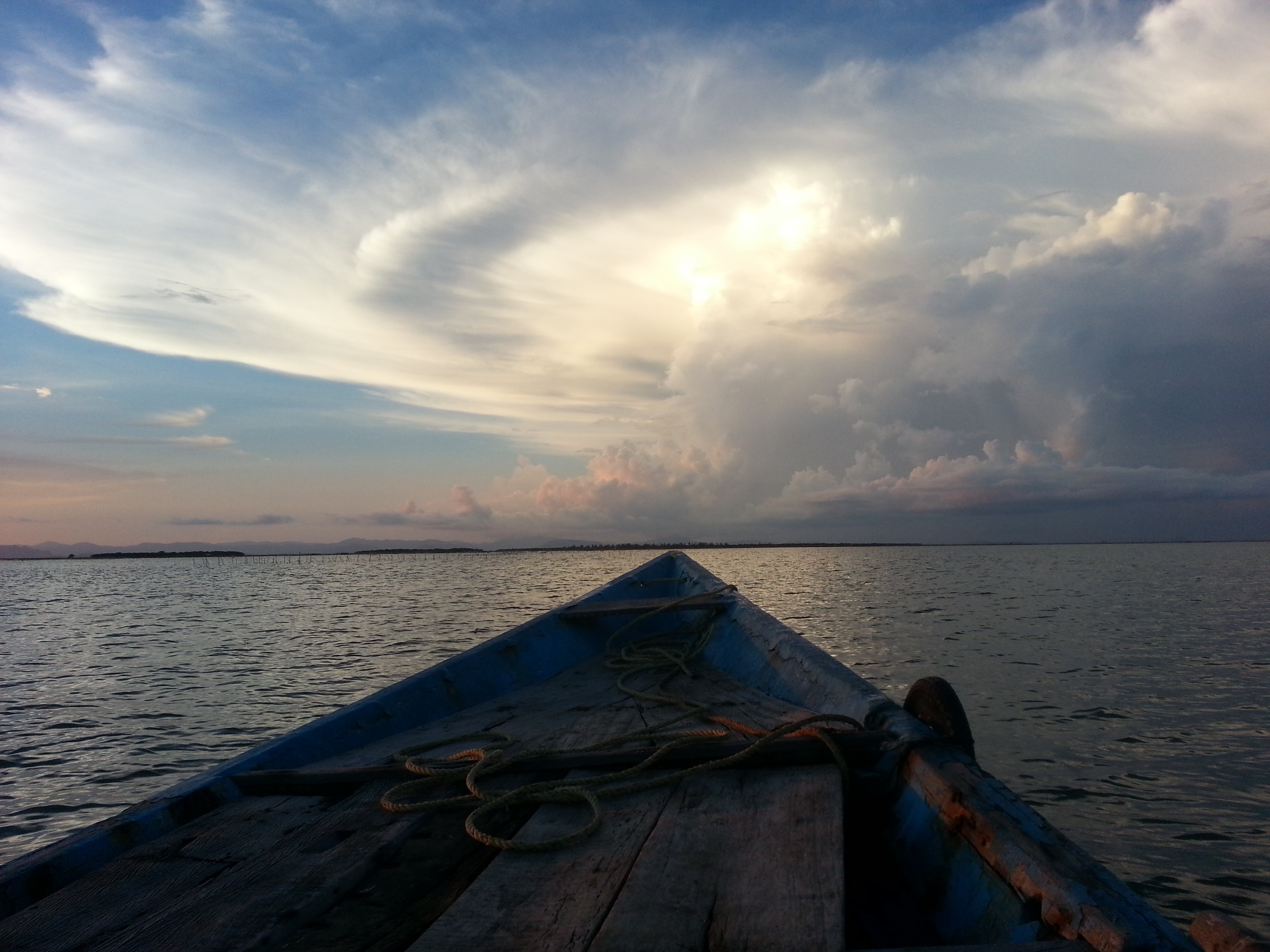 blue and brown wooden boat on body of water under cloudy sky during daytime