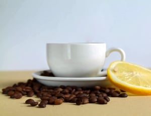 white ceramic teacup with coffee beans and slice lemon thumbnail