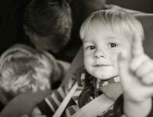 grayscale photo of baby and another boy behind thumbnail