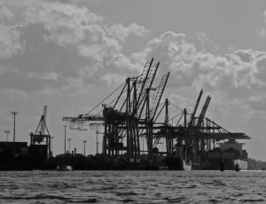 silhouette of a tower crane near body of water thumbnail