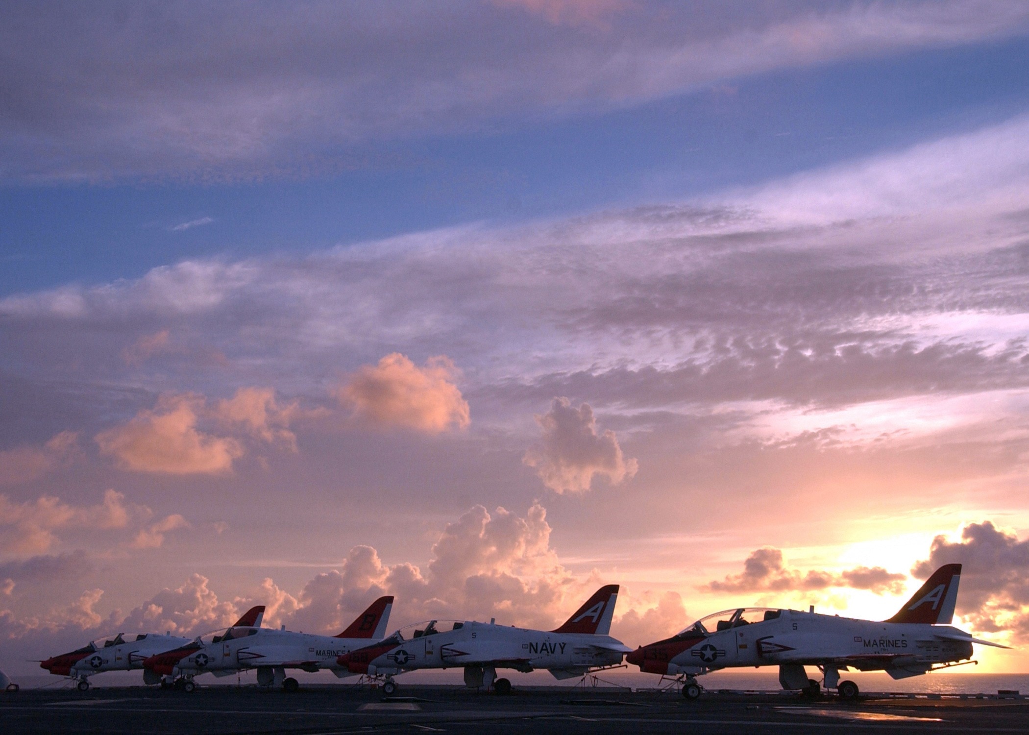 four parked fighter planes during golden hour