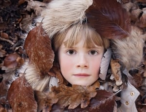 toddler's brown winter coat covered by brown leaf thumbnail