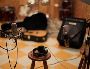 black headphones on brown wooden round chair near condenser microphone thumbnail