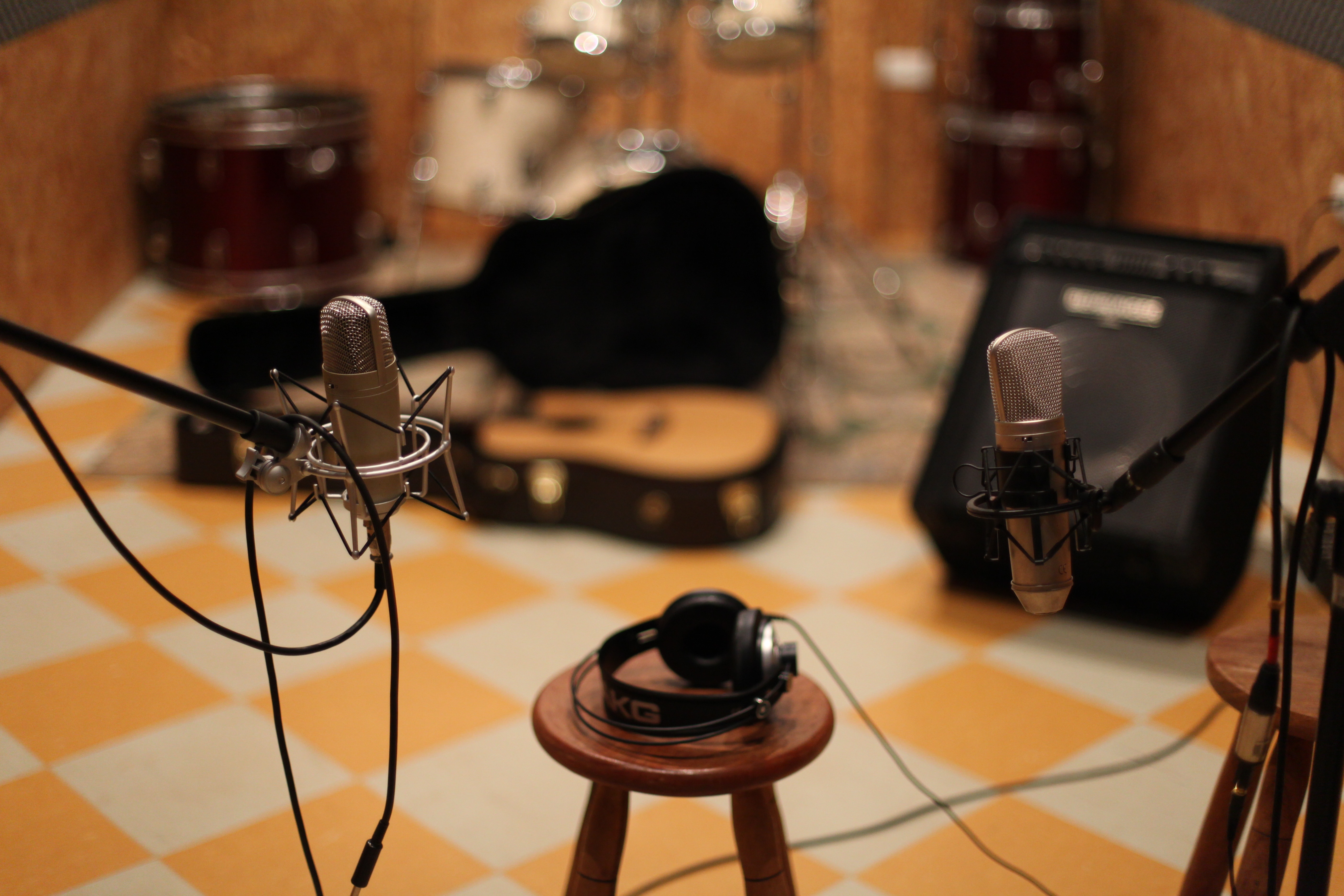 black headphones on brown wooden round chair near condenser microphone