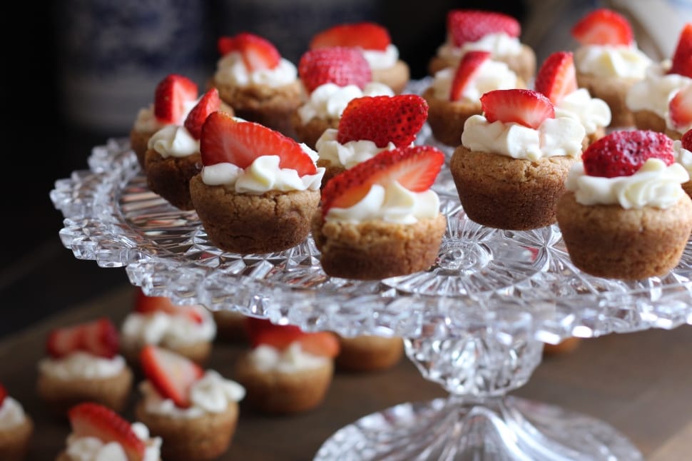 mini cupcakes topped with white cream and sliced strawberries preview
