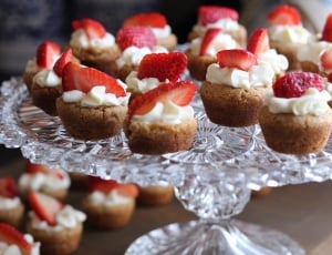 mini cupcakes topped with white cream and sliced strawberries thumbnail