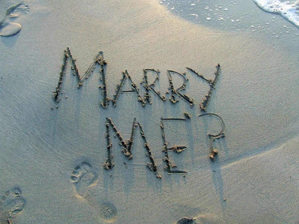 Marry me sand text on shore during daytime preview
