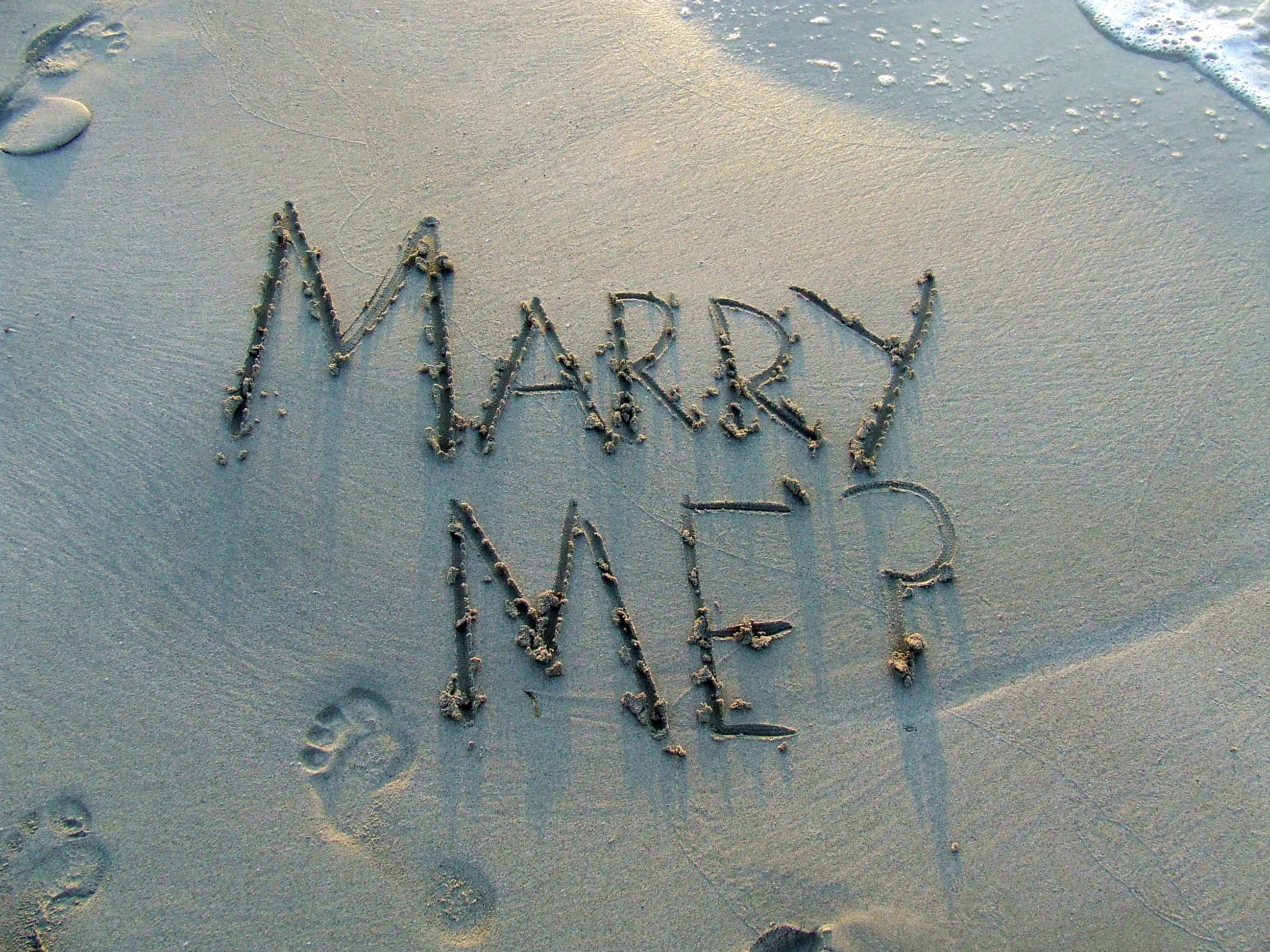 Marry me sand text on shore during daytime