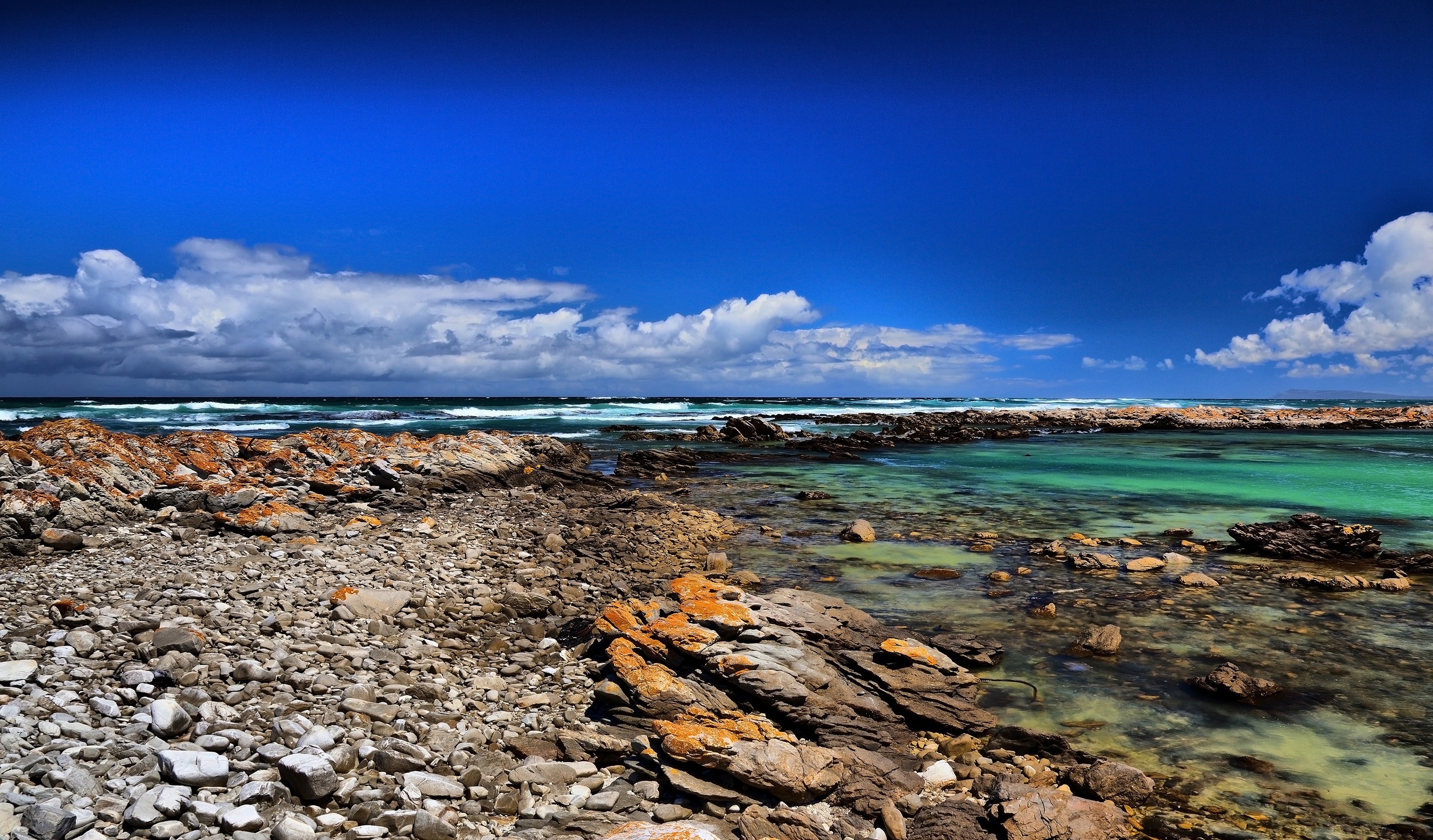 rocky sea shore under blue and cloudy sky