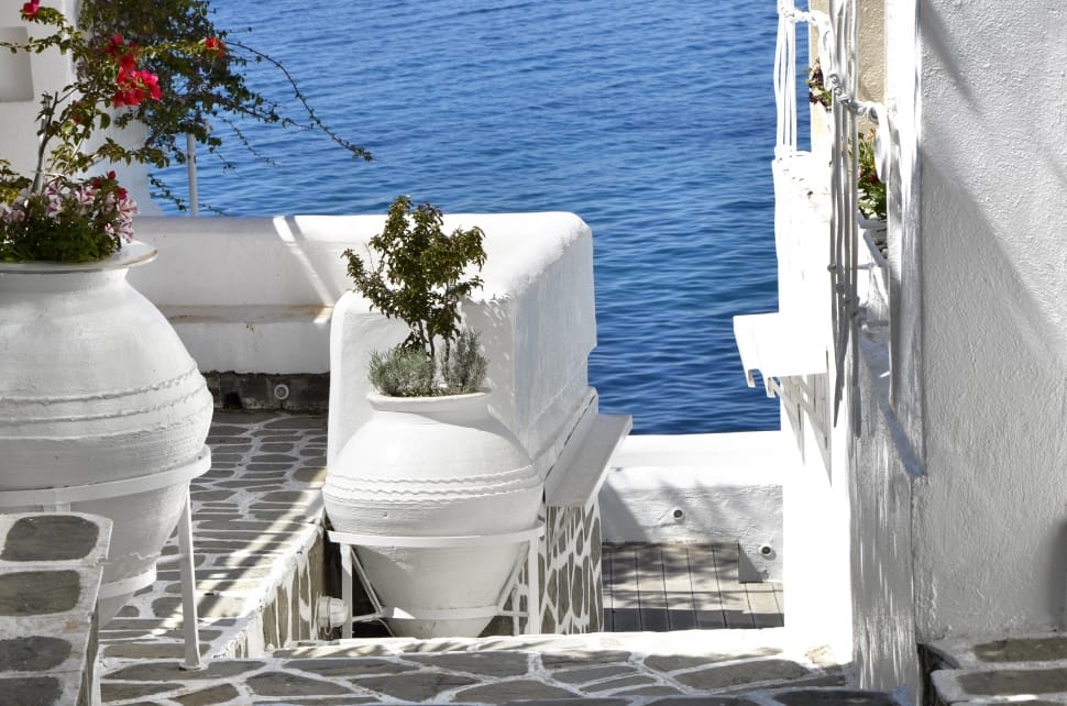 white concrete balcony with vases near ocean during daytime preview