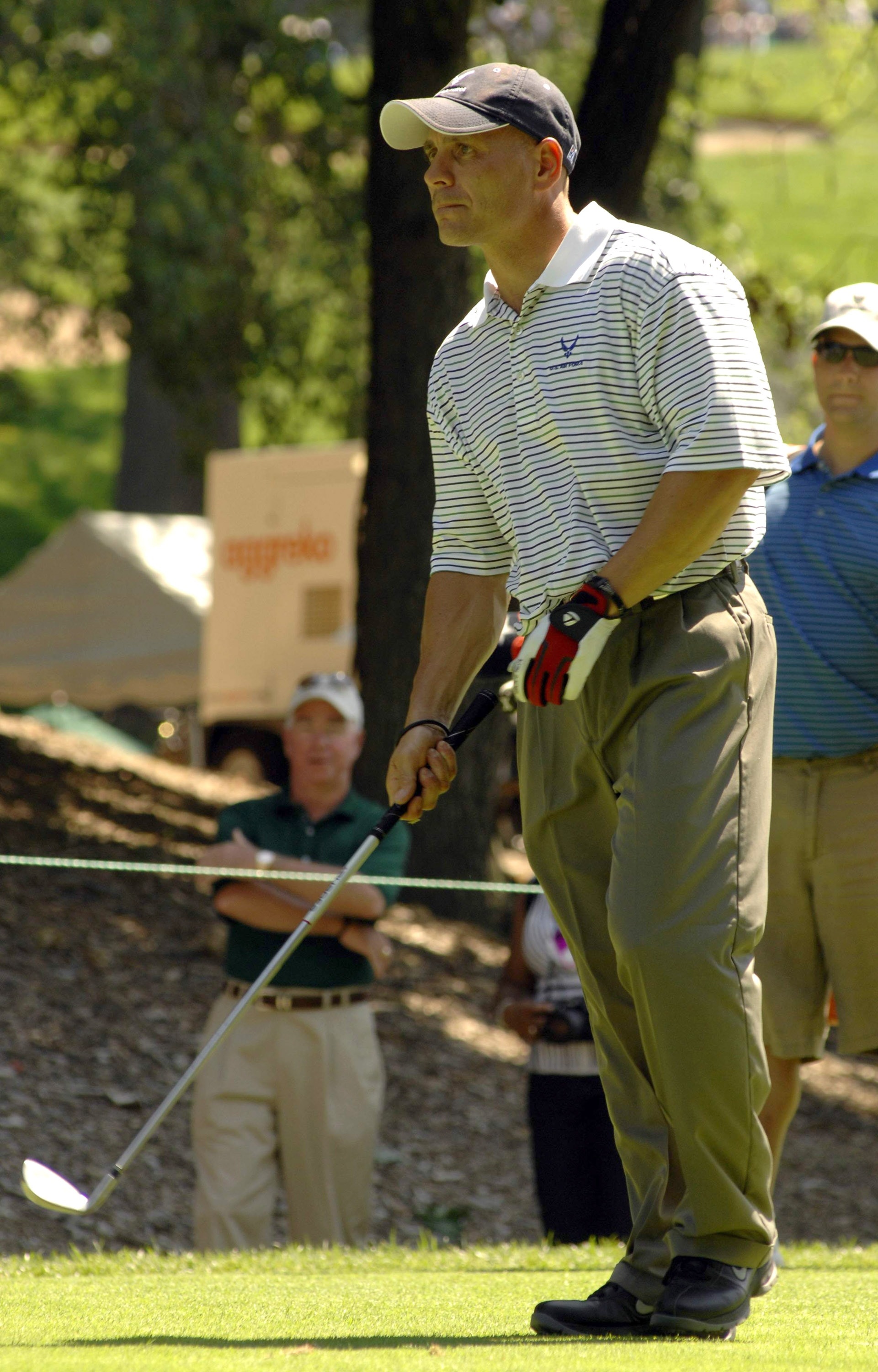 man in gray polo shirt and green dress pants playing golf