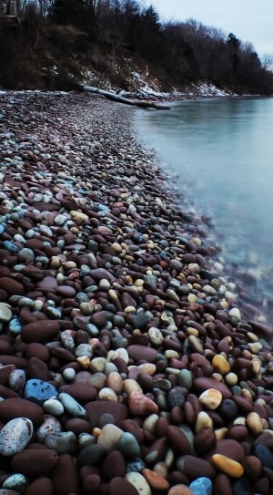 pebbles in shore beside body of water thumbnail