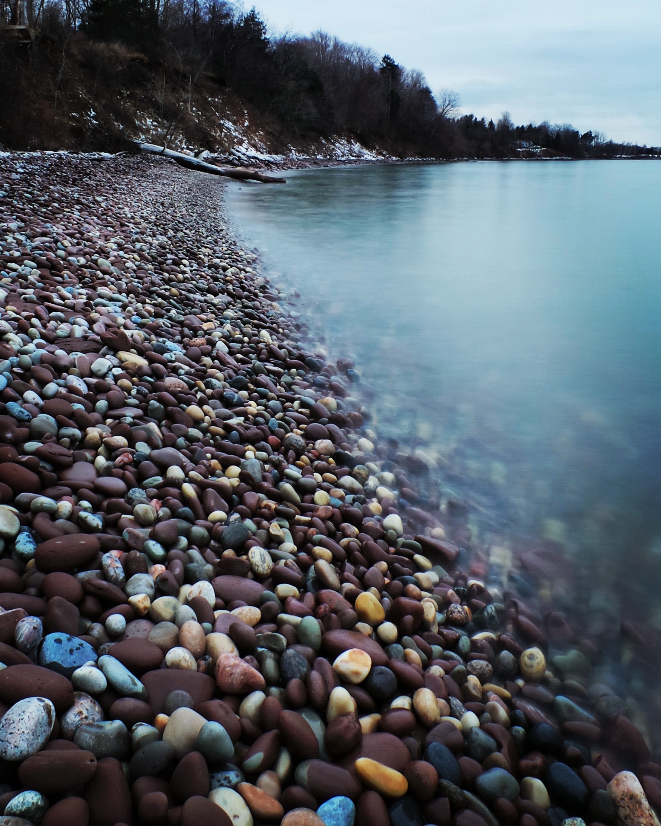 pebbles in shore beside body of water