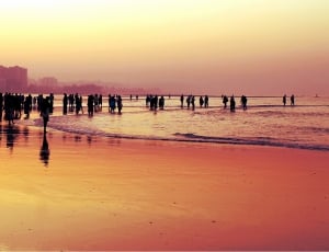 silhouette of people walking on beach during sunset thumbnail