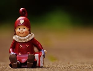 boy in red trench coat and hat sitting on floor in shallow focus photography thumbnail