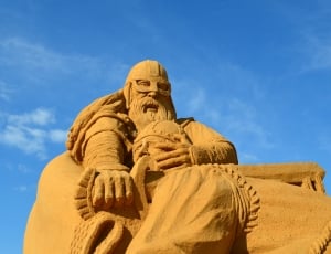 statue of two men beheading the other man photo taken under blue sky thumbnail
