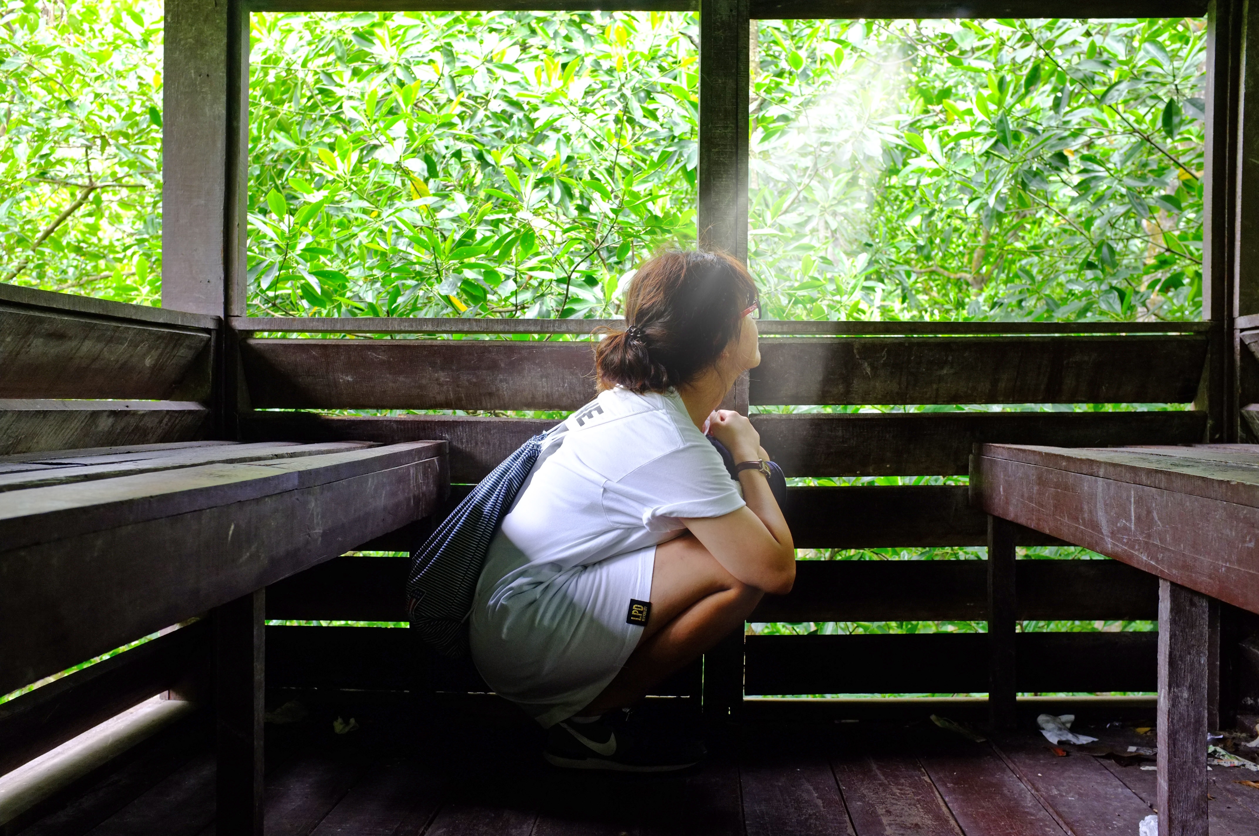 woman wearing white t-shirt sitting on a wooden room during daytime