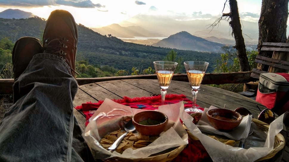 person's feet on table beside dish and champagne glasses during daytime preview