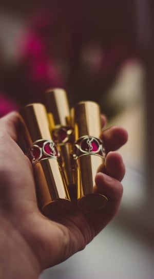 person holding three gold lipsticks thumbnail