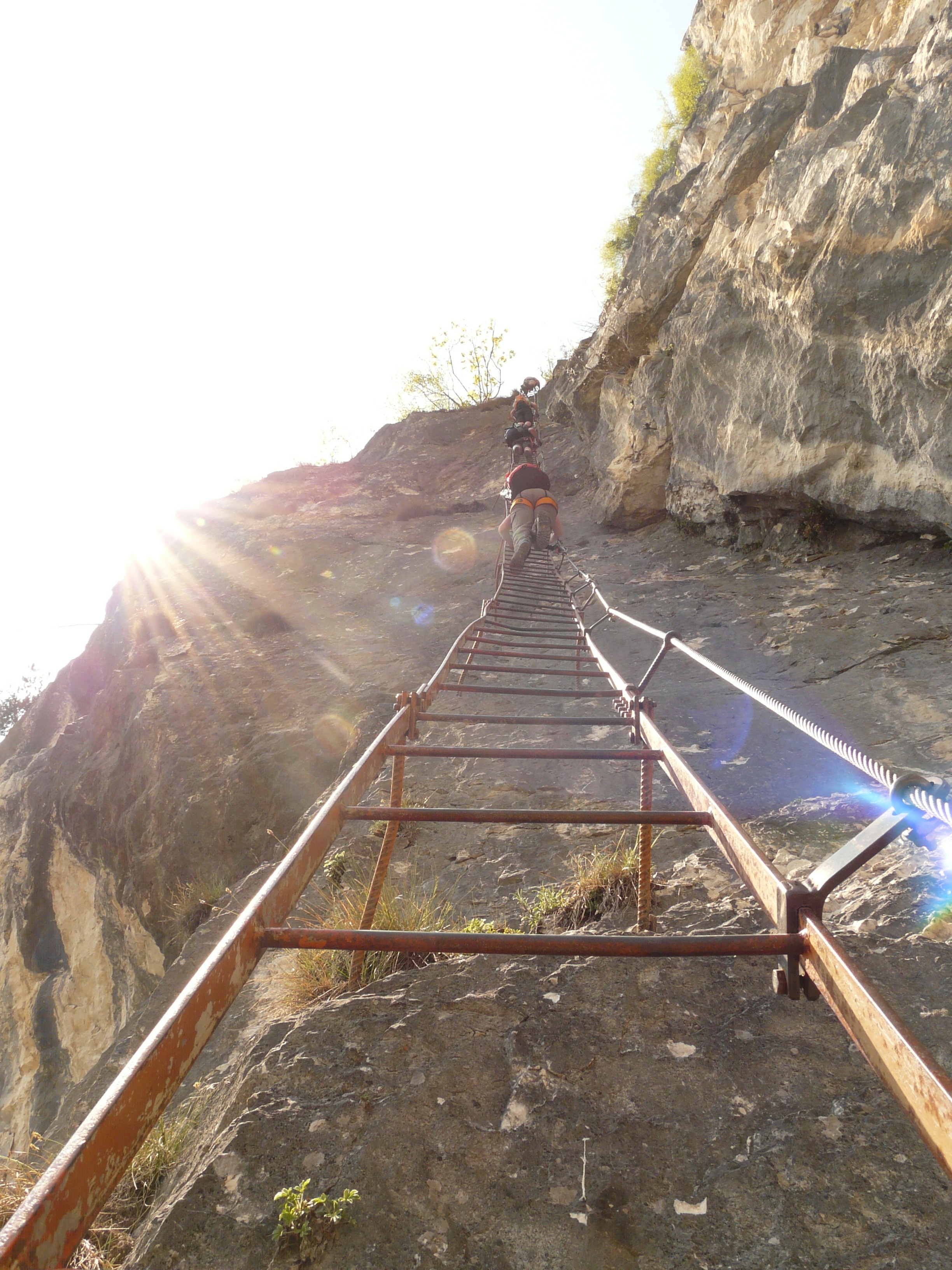 people climbing on brown steel ladder on grey rock mountain during dyatume