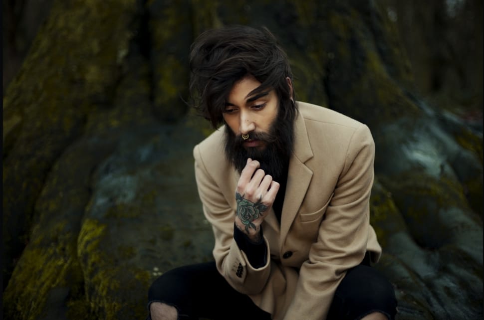 men's wearing brown suit jacket sitting in tree with green tattoo in hand preview