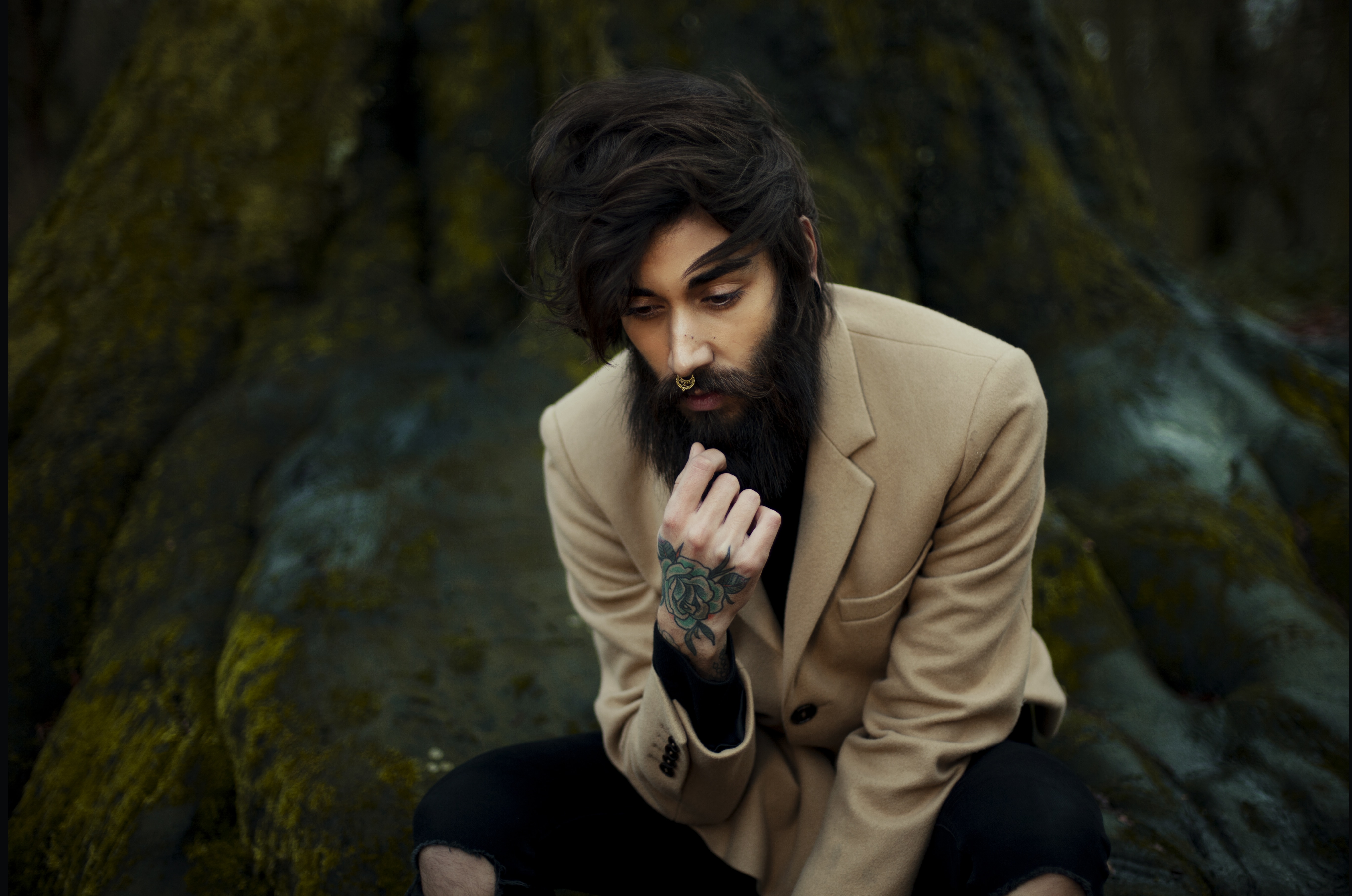 men's wearing brown suit jacket sitting in tree with green tattoo in hand