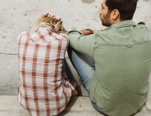 two persons sitting on cement pavement thumbnail